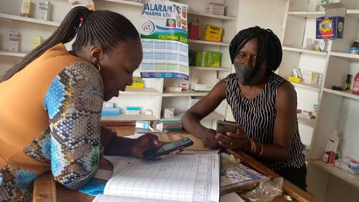 Coaching on data capture and reporting for a drug-shop attendant at Buikwe District, Uganda.Photo courtesy: Buikwe Family Planning health team.